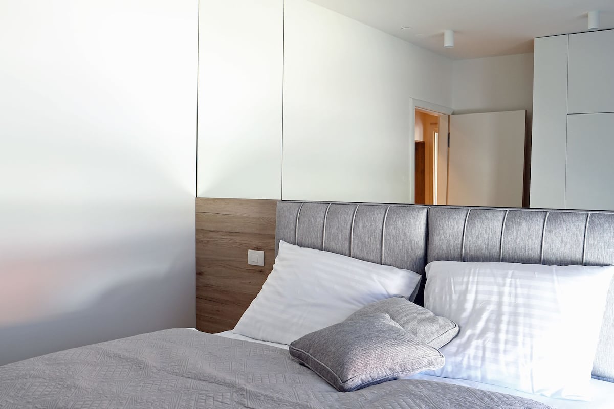 Un dormitorio moderno con una cama grande, cabecera y espejo.