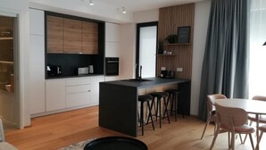 A modern kitchen with a central island, bar stools, and a dining area with a round table and chairs.