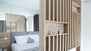 A modern bedroom with a bed, a wooden slatted wall, and a shelf with the word "LOVE".
