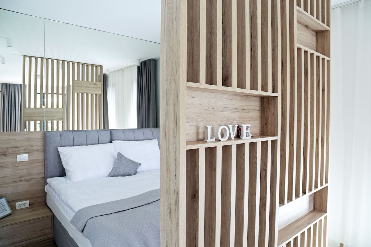 Un dormitorio moderno con una cama, una pared de listones de madera y un estante con la palabra 'LOVE'.
