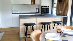 A modern kitchen with a central island, bar stools, and a dining area with a table set for two.