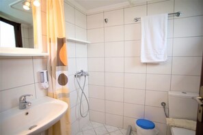 Ett badrum med handfat, dusch och toalett.