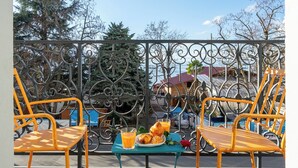 A patio with yellow chairs and a table with a plate of food and a glass of orange juice. - Montreux Grand Rue Apartments (Montreux)