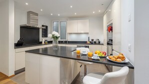 A modern kitchen with a central island, white cabinetry, and a stainless steel range hood. - Montreux Grand Rue Apartments (Montreux)