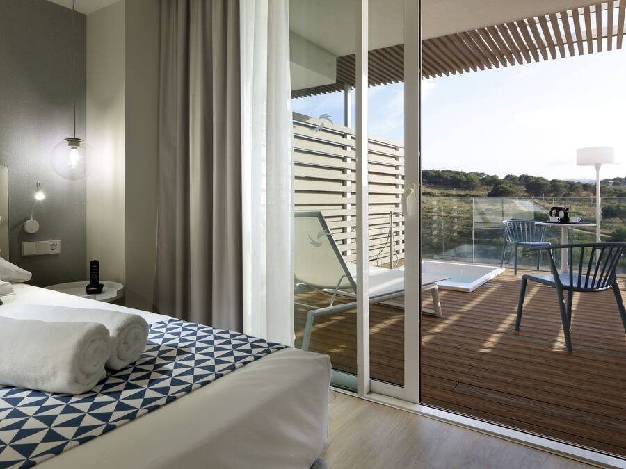 Camera d'albergo moderna con un grande letto, un comodino e vista sulla terrazza esterna.