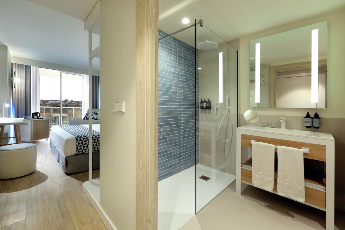 Un baño moderno con cabina de ducha de vidrio, un espejo grande y tocador con toallas.