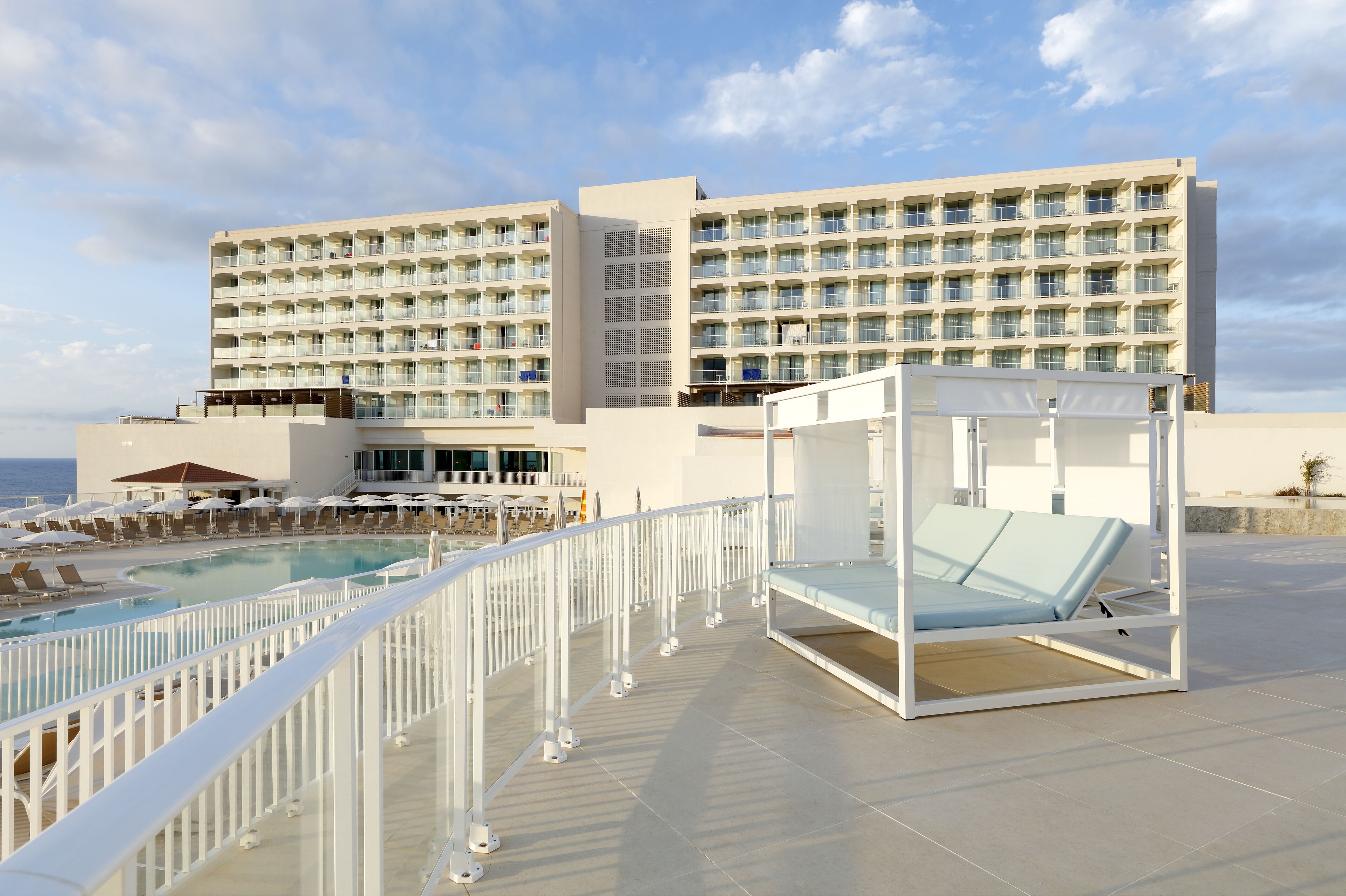 Un hôtel doté d’une piscine, de chaises longues et d’un cabanon.