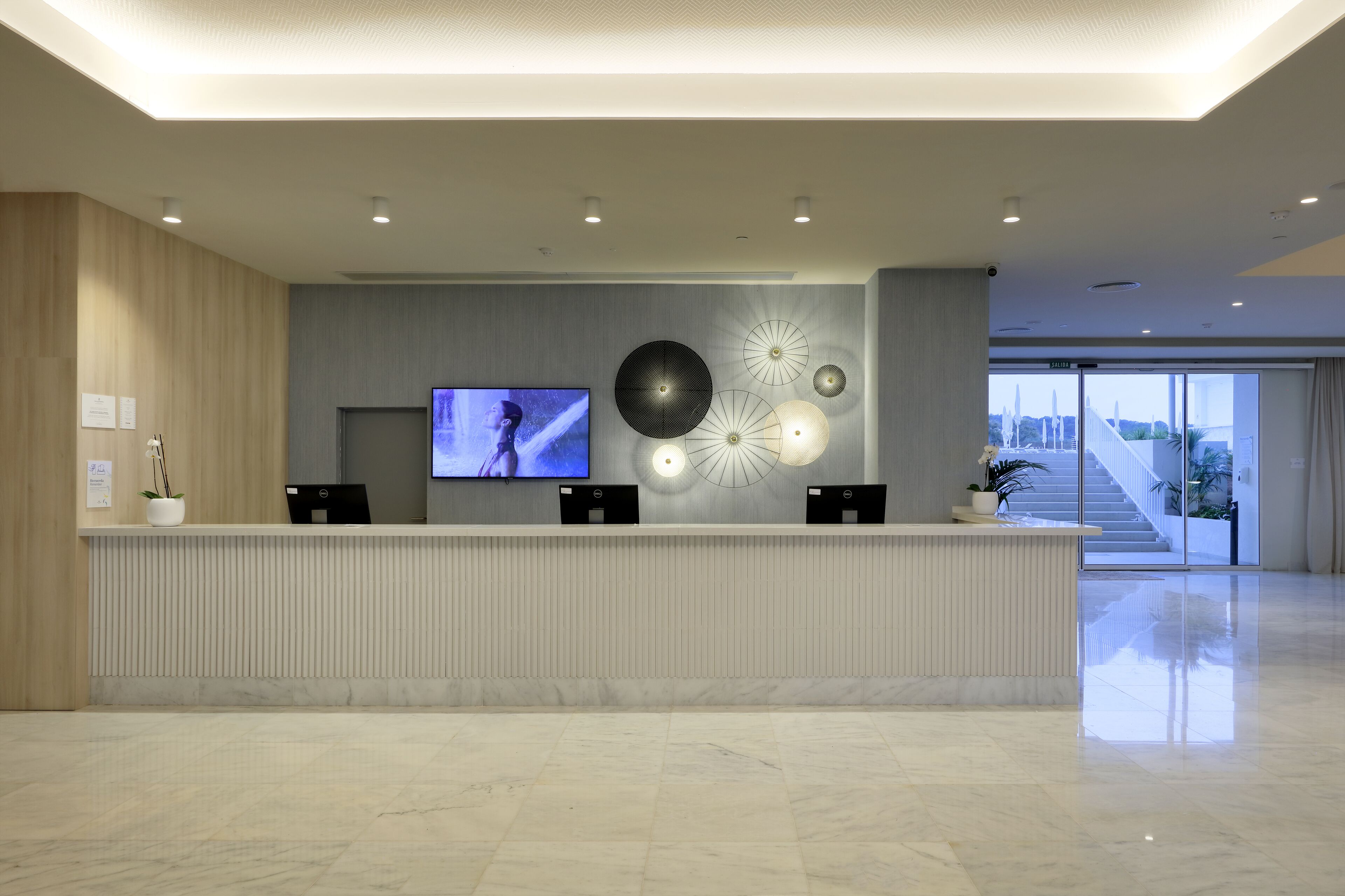A modern reception area with a marble floor, a flat-screen TV, and decorative wall art.