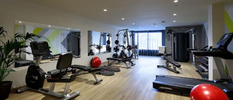 Une salle de sport moderne équipée de machines de cardio, de matériel de musculation et d’un tapis de course.