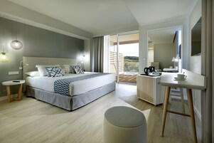 Ein modernes Hotelzimmer mit einem großen Bett, einem Schreibtisch und einem Balkon mit Blick.