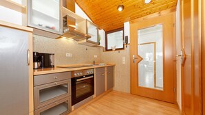 A compact kitchen with stainless steel appliances, wooden cabinets, and a wooden floor. - Altes Eichamt (Bernkastel-Kues)