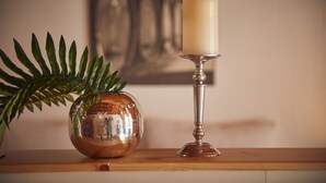 A candle on a silver holder, a reflective spherical object, and a fern on a wooden surface. - Altes Eichamt (Bernkastel-Kues)