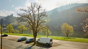 A parking area with a white van, a tree, and a view of a castle on a hill. - Altes Eichamt (Bernkastel-Kues)