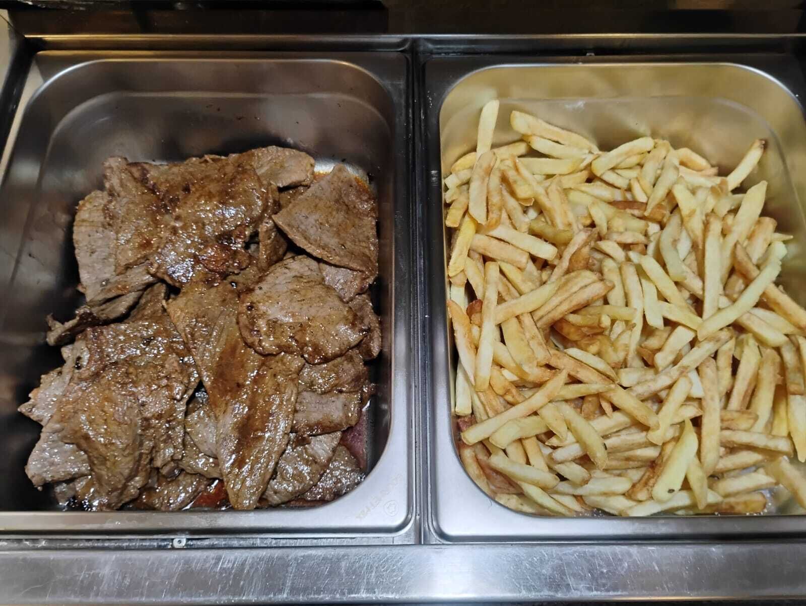 Dos recipientes de acero inoxidable, uno con carne de res en rodajas y el otro con papas fritas.