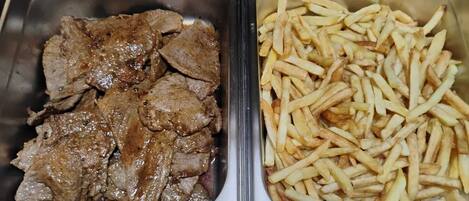 Dos recipientes de acero inoxidable, uno con carne de res en rodajas y el otro con papas fritas.