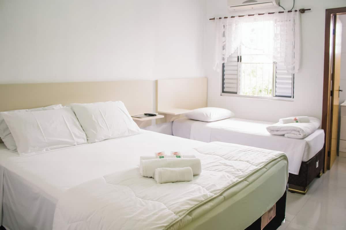 A hotel room with two beds, a nightstand, and a window with blinds.