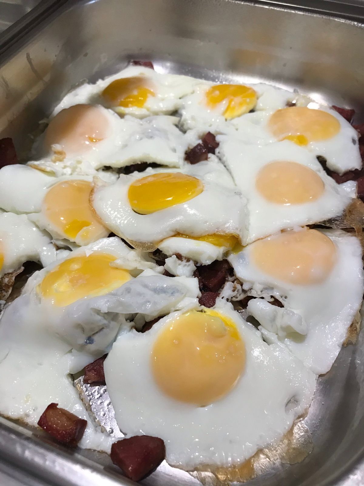 A stainless steel sink with eggs and bacon.