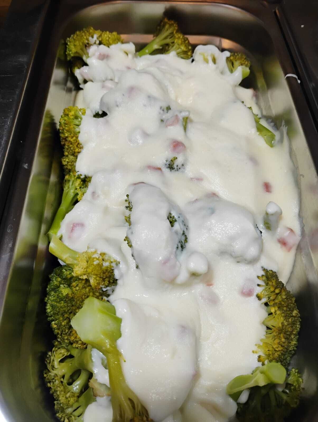 A dish of broccoli covered in a creamy sauce.