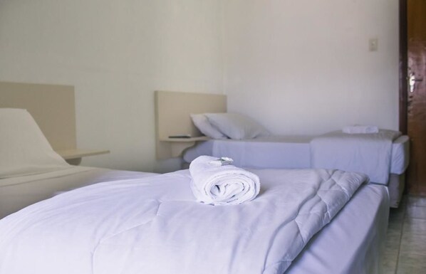 Una habitación de hotel con dos camas, cada una con una almohada y una toalla enrollada.