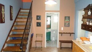 Een trap die leidt naar een badkamer met een spiegel, een handdoekhouder en een bordje aan de muur.