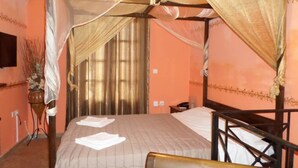 Een hemelbed met baldakijn, een nachtkastje en een aan de muur bevestigde televisie.
