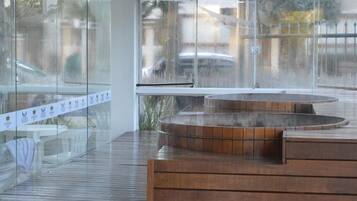 A modern indoor space with a wooden bench and a glass wall reflecting a street scene.