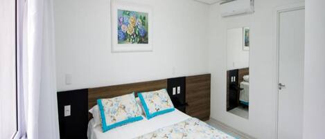 A bedroom with a bed, a painting on the wall, and a door.