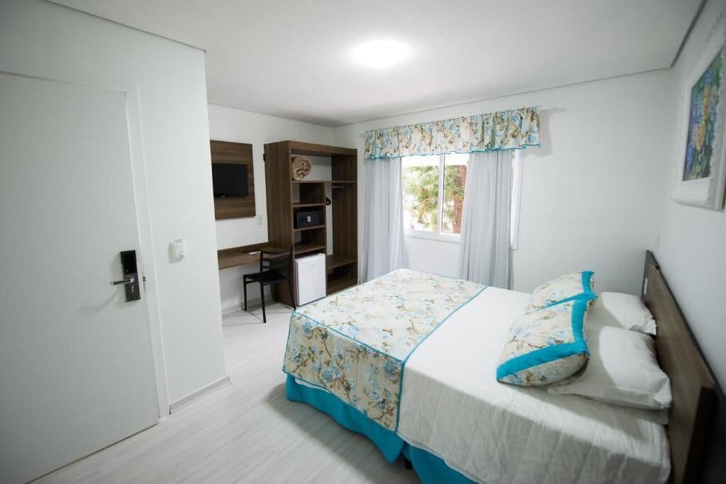 A bedroom with a bed, a desk, and a wardrobe.