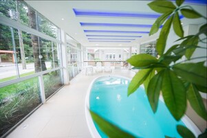 Una piscina interna con pareti in vetro, vista sull'esterno e soffitto illuminato di blu.