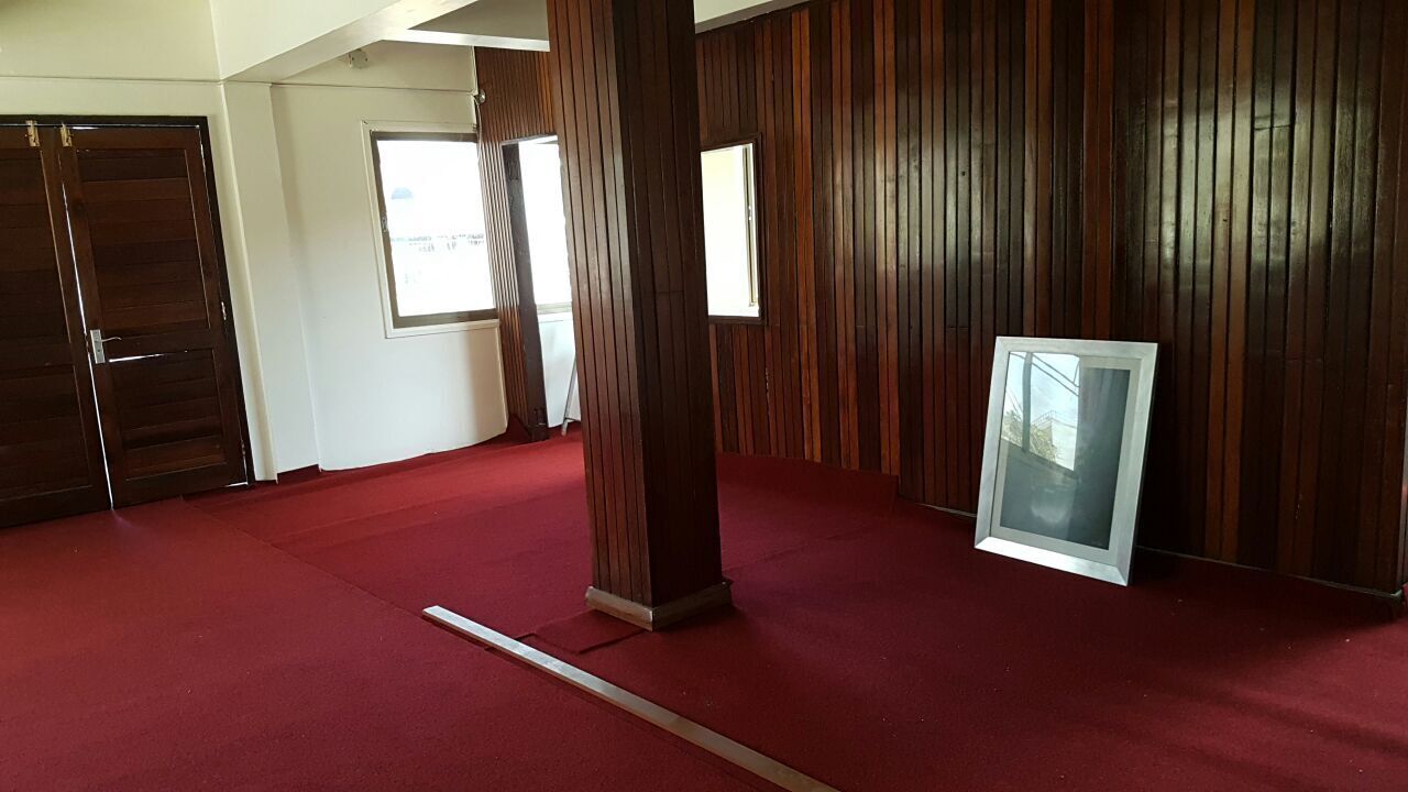 Una habitación con alfombra roja, paneles de madera en las paredes, un ventanal y una puerta.