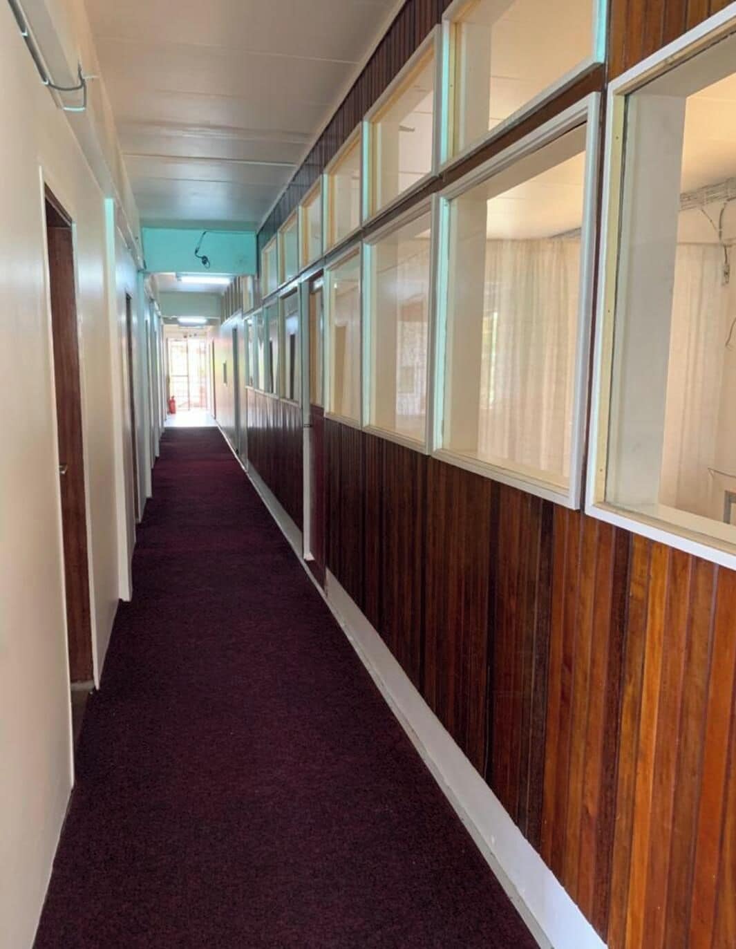 A hallway with wooden paneling and large windows.