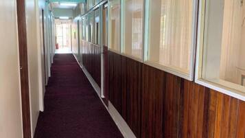 A hallway with wooden paneling and large windows.