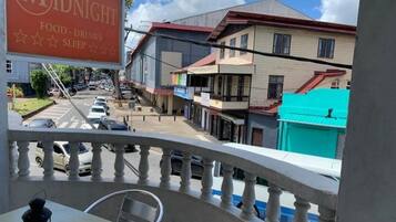 A balcony with a view of a street, a sign for 'Midnight Food-Drinks Sleep', and a building with a red roof.