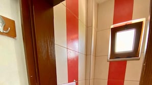 A small bathroom with a toilet, a sink, and a window. - Uysal Pansiyon (Bozcaada)