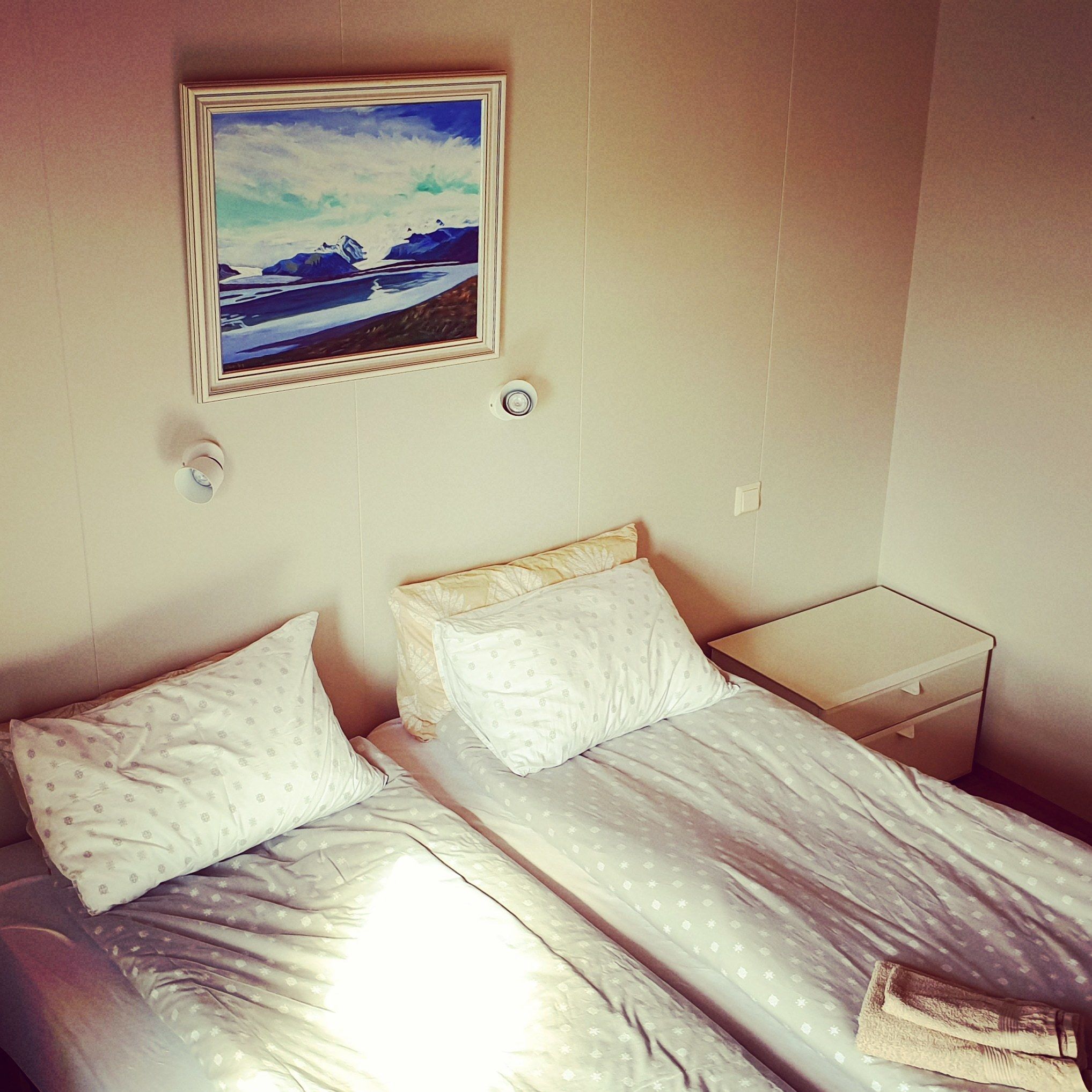 Un dormitorio con dos camas, una mesita de noche y un cuadro en la pared.