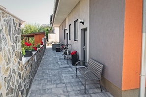 Un stretto corridoio esterno con pareti in pietra, una panchina e una bicicletta.