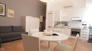 Uma sala de estar moderna com sofá, mesa de jantar com cadeiras e área de cozinha com armários e eletrodomésticos.