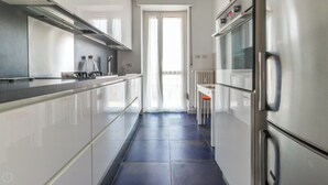 A modern kitchen with stainless steel appliances, a black countertop, and a blue tiled floor. - Italianway - Pichi 19 (Milan)