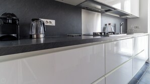 A modern kitchen with a black countertop, stainless steel appliances, and white cabinetry. - Italianway - Pichi 19 (Milan)