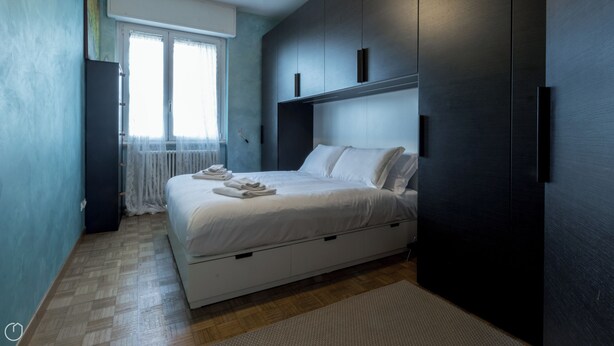 A modern bedroom with a bed, a wardrobe, and a window with curtains. - Italianway - Pichi 19 (Milan)