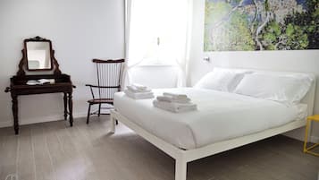 Un dormitorio con cama, una silla, un escritorio y un cuadro en la pared.