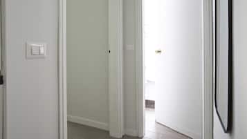 Un pasillo con paredes blancas, un interruptor de luz y una puerta con pomo.