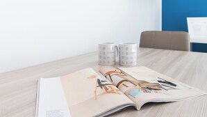 Eine auf einem Tisch liegende Zeitschrift, ein Paar Schuhe und ein Stift.