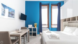 A hotel room with a bed, a desk, a chair, a TV, and a window with curtains. - Italianway - Napo Torriani 22 B (Milan)