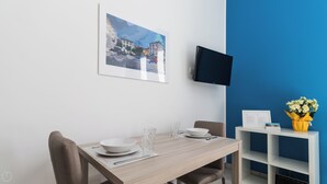 Ein Essbereich mit Holztisch, Stühlen, einem an der Wand montierten Fernseher und einer blauen Akzentwand.
