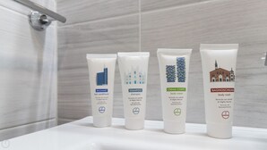 Vier Kosmetikflaschen auf einer Badezimmerablage.