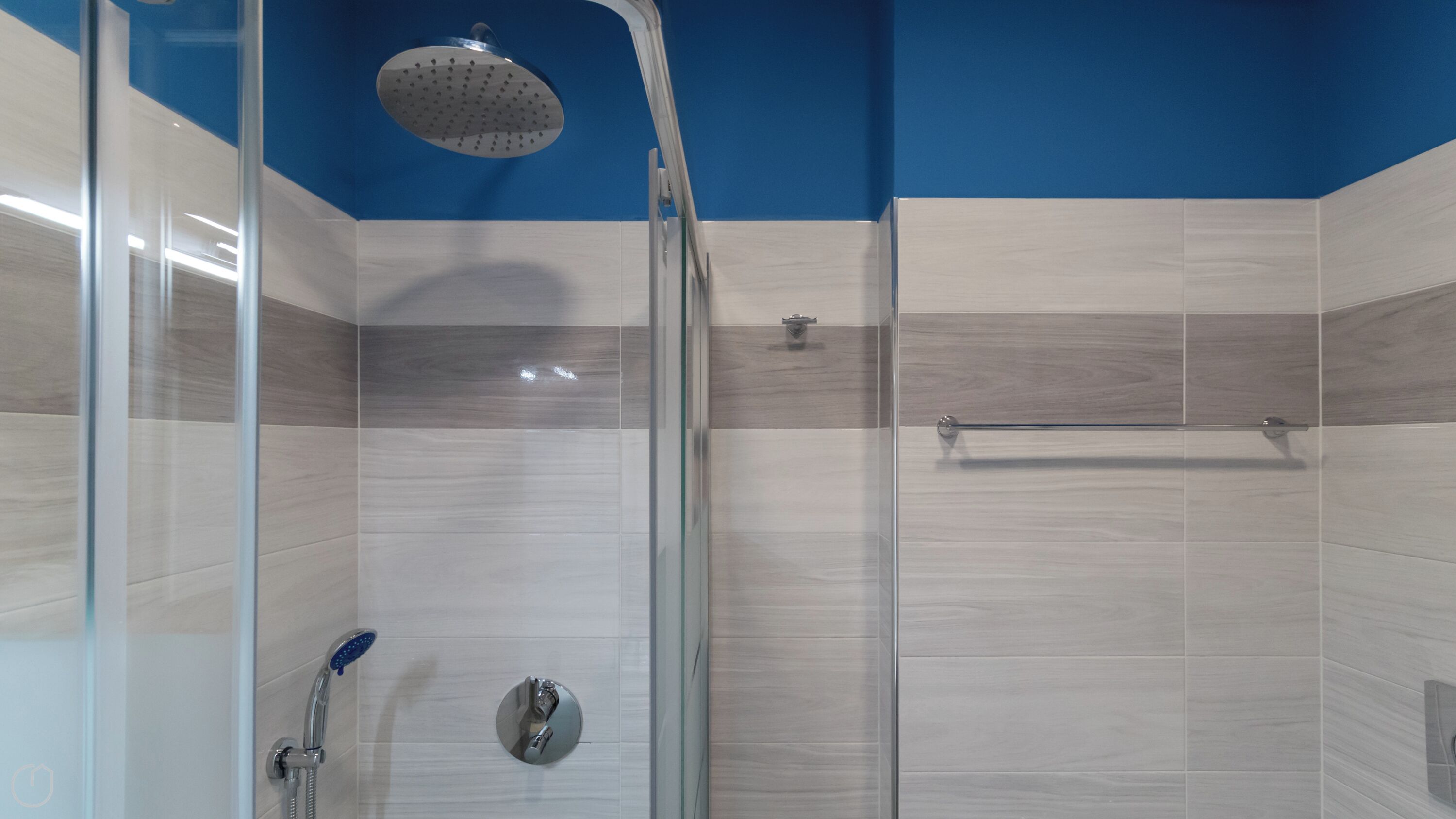 A shower with a handheld showerhead and a wall-mounted rain showerhead.