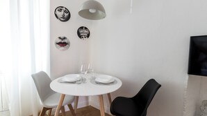A dining area with a round white table, two chairs, and a modern pendant light. - Italianway - Pasubio 12 (Milan)