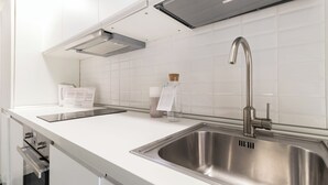 A modern kitchen with stainless steel appliances, a double sink, and a built-in range hood. - Italianway - Pasubio 12 (Milan)