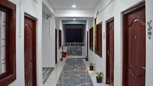 A corridor with marble flooring, wooden doors, and potted plants. - Hotel Value (Port Blair)